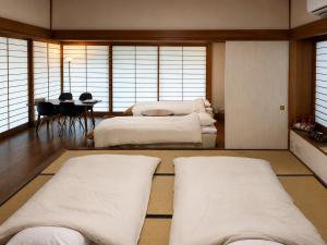 a room with three beds and a table with chairs at 春まち in Ito