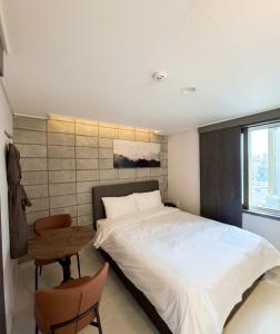 a bedroom with a bed and a table and a window at 스테이큐브 505 in Chŏnju-yŏk