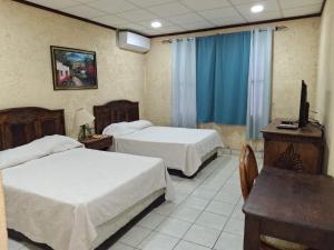 a hotel room with two beds and a television at Hotel La Estacion in La Unión