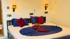 a bed with red and blue pillows on it at Arugam Bay Holiday in Arugam Bay