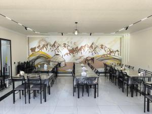 a dining room with tables and chairs and a mural at Амир in Arkit