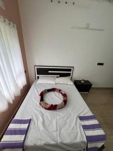a bed with a red and white pillow on it at Kurishingal Guest House in Mararikulam