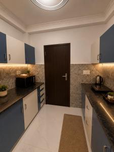 a kitchen with blue cabinets and a black door at Riwaayat & Wings, a luxe stay 5 min from Taj Mahal in Tājganj