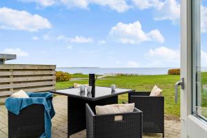 a table and chairs on a patio with a view of the ocean at Sct Knudsborg - 12E - Apartment on the beach in Brenderup