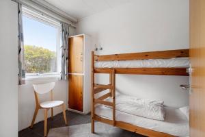 a bedroom with bunk beds with a chair and a window at Sct Knudsborg - 12E - Apartment on the beach in Brenderup