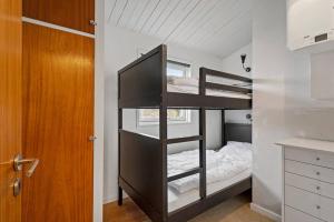 a bunk bed in a small room with a bed at Sct Knudsborg - 12H - Summerhouse on the beach in Brenderup