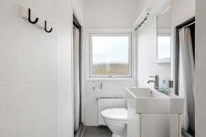 a white bathroom with a toilet and a sink at Sct Knudsborg - 12H - Summerhouse on the beach in Brenderup +24 photos