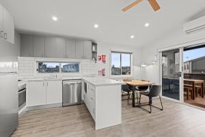 a kitchen with white cabinets and a table with chairs at Swan Bay Holiday Park in Queenscliff
