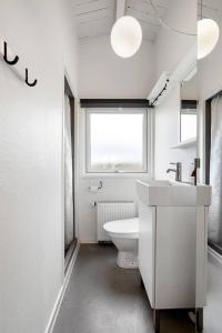 a white bathroom with a toilet and a window at Sct Knudsborg - 12J - Summerhouse on the beach in Brenderup +17 photos