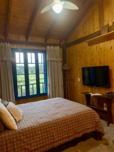 a bedroom with a bed and a flat screen tv at Casa de Campo in Guaíba