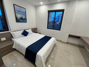 a bedroom with a bed and two windows at Sealand hotel & spa in Dong Hoi