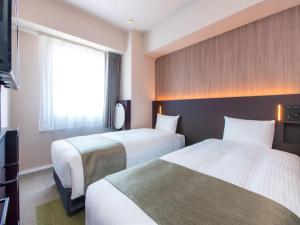 a hotel room with two beds and a television at Villa Fontaine Tokyo Kudanshita in Tokyo
