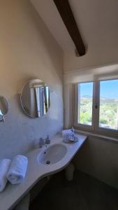 a bathroom with a sink with a mirror and a window at Stazzu La Vigna Di Maria in Aglientu