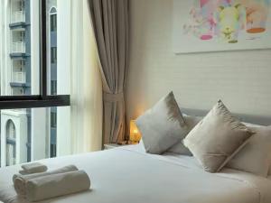 a white bed with pillows in a room with a window at Title Naiyang Walk To Beach C111 in Nai Yang Beach