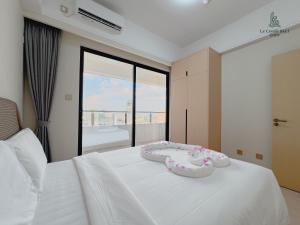 a white bed with two hello kitty shoes on it at Le Conde Maison in Phnom Penh +44 photos
