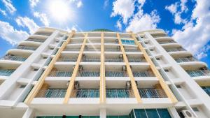 a tall white building with the sun in the sky at Olive Hotel & Residence Bangkok Sukhumvit 101 near True Digital Park in Bangkok