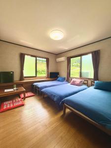 a room with three beds and a tv and windows at Takumisou 2 in Kiso