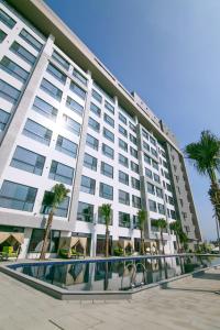 斗六的住宿－三好國際酒店，一座白色的大建筑,前面有棕榈树