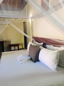 a bed with white pillows on top of it at Nkanga Hotel in Kasane