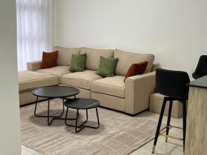 a living room with a couch and two tables at Serenity Residences 1BR Ruaka Near Two Rivers & UN Gigiri in Nairobi