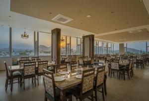 a dining room with tables and chairs and windows at Tripli Regalia Mayur Palace in Udaipur