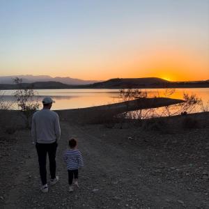 a man and a child walking along a lake at sunset at DAR agafay in Lalla Takerkoust