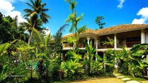 a house with palm trees in front of it at Charleston's Ahangama in Ahangama