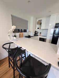 a kitchen with a white counter and two chairs at Surfers 641 in Gold Coast