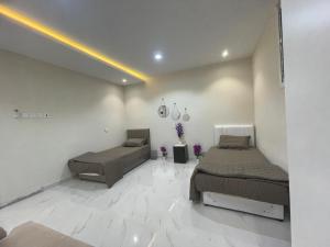 two beds in a room with white tile floors at Green Stays in Comilla