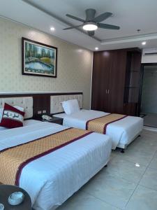 a hotel room with two beds and a ceiling fan at Khách sạn Rosy in Hòa Ðình