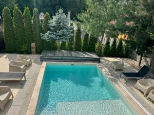 a swimming pool in a yard with chairs and trees at Mineral apartman Smaragd in Nyíregyháza