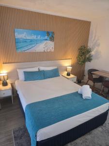 a bedroom with a large bed with blue and white sheets at Alexandra Park Motor Inn in Bundaberg +86 photos
