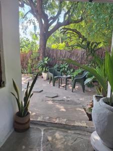a patio with chairs and a tree in a yard at The Nook,Kilifi in Kilifi