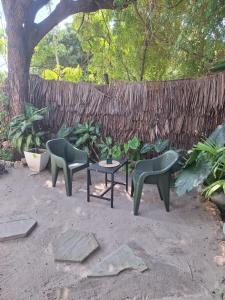 three chairs and a table in front of a fence at The Nook,Kilifi in Kilifi