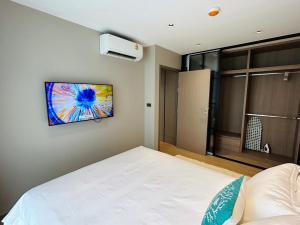 a bedroom with a bed and a tv on the wall at Tierra Residences in Bangkok