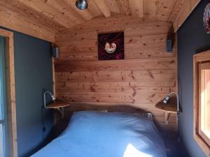 a bed in a room with a wooden wall at Notre roulotte de charme in Chevinay