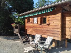 a wooden cabin with two chairs and a clock at Notre roulotte de charme in Chevinay