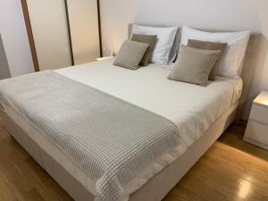 a large bed with white sheets and pillows at Delux apartment Dora with a private parking in Rijeka +53 photos