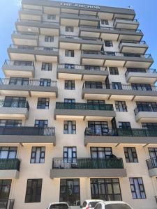 a tall building with cars parked in front of it at Serenity Residences 1BR Ruaka Near Two Rivers & UN Gigiri in Nairobi