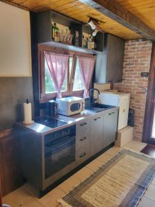 a kitchen with a stove and a microwave at Kuća za odmor Čanić gaj in Gospić
