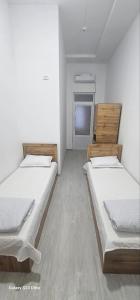 two beds in a room with white walls and wooden floors at Magnato Hostel in Andizhan