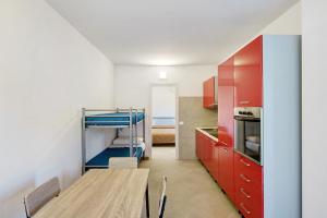 a kitchen with red cabinets and a wooden table at Mammina Holiday Home in Casal Velino