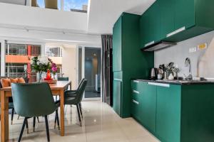 a kitchen with green cabinets and a table with chairs at Luxurious Penthouse Pattaya in Pattaya South