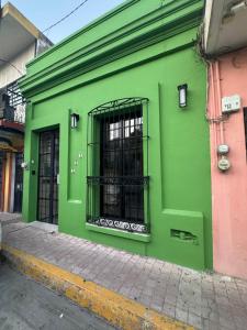 a green building with a barred window on a street at Casa MARTINA in Villahermosa +17 photos