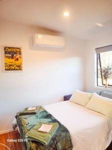 a bedroom with a white bed with avertisementatronatronstrationstration at The She Oak in Carterton