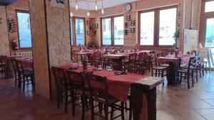 a dining room with tables and chairs and windows at Albergo Rusen in Borno