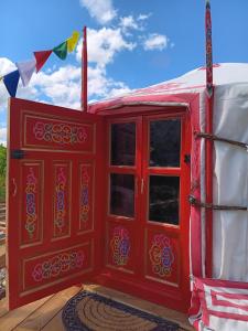 a red door of a red tent with flags at Notre yourte mongole in Chevinay