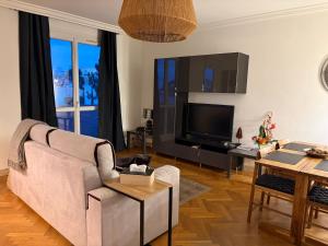 a living room with a couch and a tv at Le Relais des Cyclamens Bron in Bron
