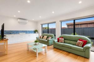 a living room with two green couches and a table at Mercer on Port in Portarlington