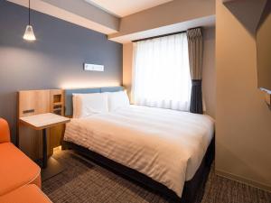a hotel room with a bed and a window at Comfort Hotel ERA Sapporo North in Sapporo
